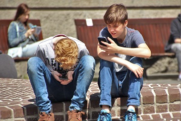 Jugendliche mit Smartphones vor der Schule