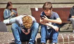 Jugendliche mit Smartphones vor der Schule