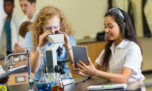 High school-Schüler mit digitalen tablet und Mikroskop in class