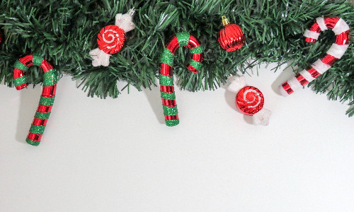 Eine weihnachtliche Girlande aus Tannenzweigen, geschmückt mit Glaskugeln und Zuckerstangen